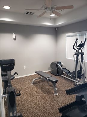 Corcoran apartment for rent - A home gym with a variety of equipment including a treadmill, weights, and a bench.