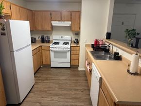 Huron apartment for rent - A kitchen with a white fridge, white stove, and wooden cabinets.