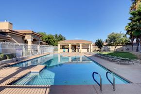 Henderson apartment for rent - A large outdoor swimming pool with a diving board and a building in the background.