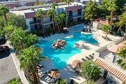 Las Vegas apartment for rent - A pool surrounded by palm trees and umbrellas.