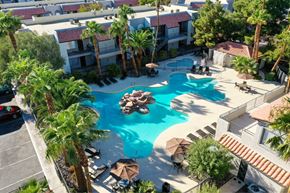 Las Vegas apartment for rent - A pool surrounded by palm trees and umbrellas.