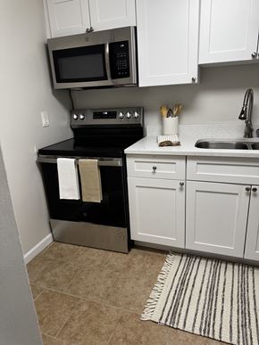 Spartanburg apartment for rent - A kitchen with white cabinets and a black stove top oven.