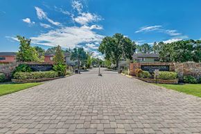 Tampa apartment for rent - A brick pathway leads to a building with a sign at Westminster Chase Apartments, Tampa, FL, 33616