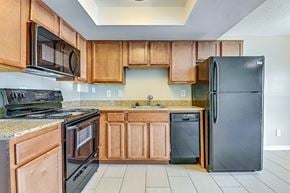 Tampa apartment for rent - A kitchen with wooden cabinets and black appliances. at Westminster Chase Apartments, Tampa, 33616
