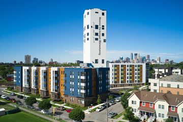 Minneapolis apartment for rent - A tall white building with the words "Maison du Shingle Mansioning" on it stands in front of a row of other buildings.