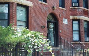 Minneapolis apartment for rent - A red brick building with a black gate and a sign on the wall.