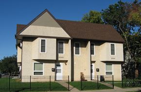 Minneapolis apartment for rent - a tan brick house with a fence in front of it