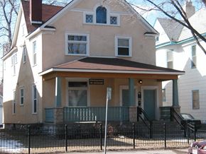 Minneapolis apartment for rent - A two-story house with a green door and a sign on the front porch.