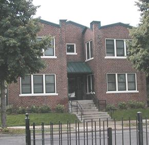 Minneapolis apartment for rent - A red brick house with a green awning and a black fence in front.