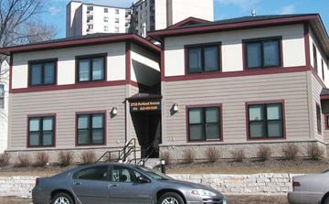 Minneapolis apartment for rent - A grey car is parked in front of a building with a red and white striped awning.