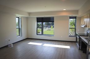 Saint Paul apartment for rent - A large empty room with a kitchen area to the right and a view of a green lawn through the windows.