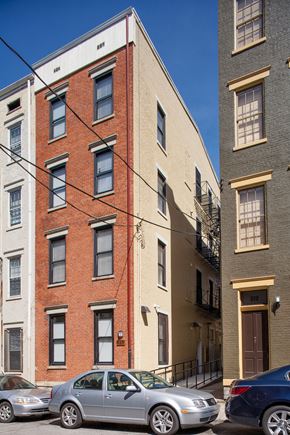 Cincinnati apartment for rent - A silver car is parked in front of a red brick building.