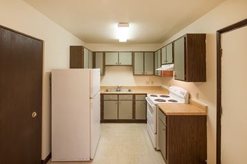Marion apartment for rent - A kitchen with a white refrigerator and brown cabinets.