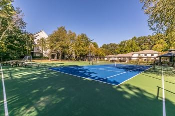 A tennis court with trees and a house in the background