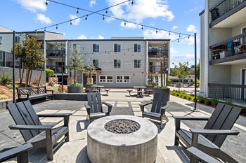 A patio with black chairs and a fire pit in front of a building.