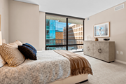 Minneapolis apartment for rent - A bedroom with a large bed and a balcony overlooking a city.