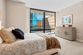Minneapolis apartment for rent - A bedroom with a large bed and a balcony overlooking a city.