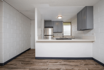 View from the living room with plank flooring into the kitchen with grey shaker-style cabinets