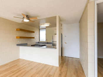 View of the kitchen with a sink and a ceiling fan from the living room with plank flooring