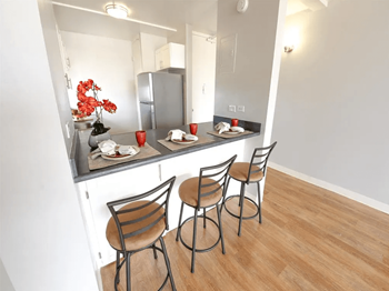 A kitchen and dining area with a breakfast bar and a stainless steel refrigerator