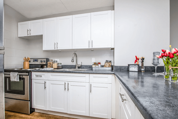 A white kitchen with marble counter tops and white cabinets