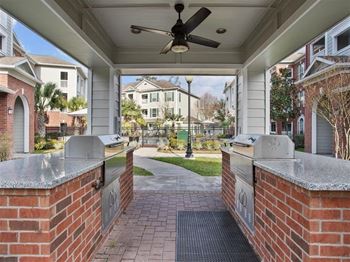 A covered outdoor kitchen with two grills and a ceiling fan