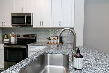 A kitchen with marble counter tops and white cabinets