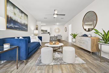 Jacksonville apartment for rent - A living room with a blue couch, a coffee table, and a painting on the wall.