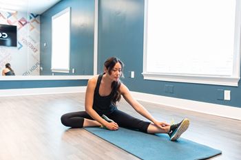 A woman sitting on a yoga mat in a yoga studio