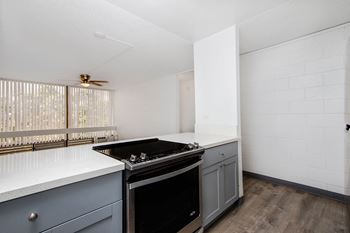 Empty kitchen with white counter tops and a black stove