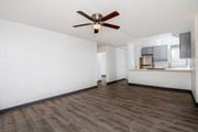 Wahiawa apartment for rent - an empty living room with a ceiling fan and a kitchen at Palms of Kilani Apartments, Wahiawa, HI, 96786