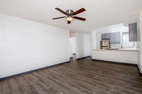Wahiawa apartment for rent - an empty living room with a ceiling fan and a kitchen at Palms of Kilani Apartments, Wahiawa, HI, 96786