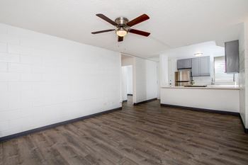 Empty living room with a ceiling fan and a kitchen