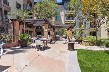 A patio area with a table and chairs surrounded by plants and trees.