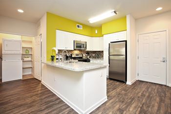 A kitchen with white appliances and a yellow accent wall.