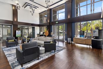 A large room with a lot of furniture and a view of trees outside the windows.