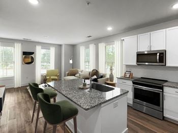 A renovated kitchen and living room with a granite counter top and white cabinets