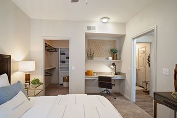A bedroom with a bed and a desk in a small room