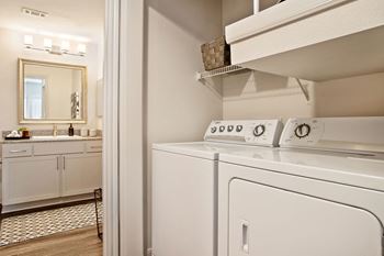 A washer and dryer in a laundry room with a sink and a mirror