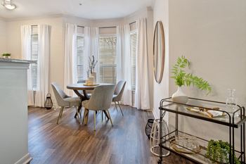 A dining room with a table and chairs and windows