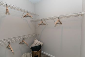 Two closets with clothes hangers and a chair in the corner of a room