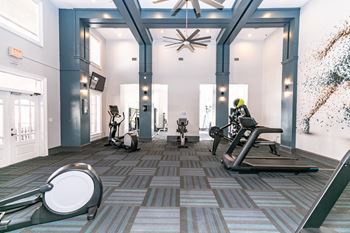 A gym with cardio equipment and a ceiling fan