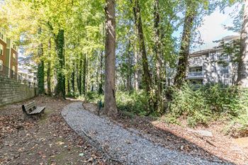 A path through the woods with a bench and a building