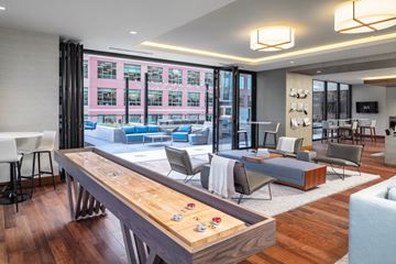 Minneapolis apartment for rent - A modern living room with a long wooden table and a view of a pink building outside the window.