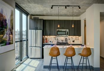 A kitchen with a bar stool and a fridge.