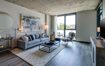 A modern living room with a grey sofa, a coffee table, and a large abstract painting on the wall.