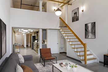 A living area with a staircase and a living room with a couch and a table