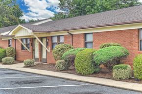 Thomasville apartment for rent - A red brick building with a brown roof and a parking lot in front.