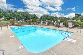 Thomasville apartment for rent - A large swimming pool surrounded by trees and lounge chairs.