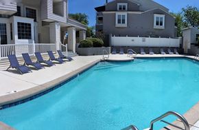 Charlotte apartment for rent - a swimming pool with blue chairs next to a house